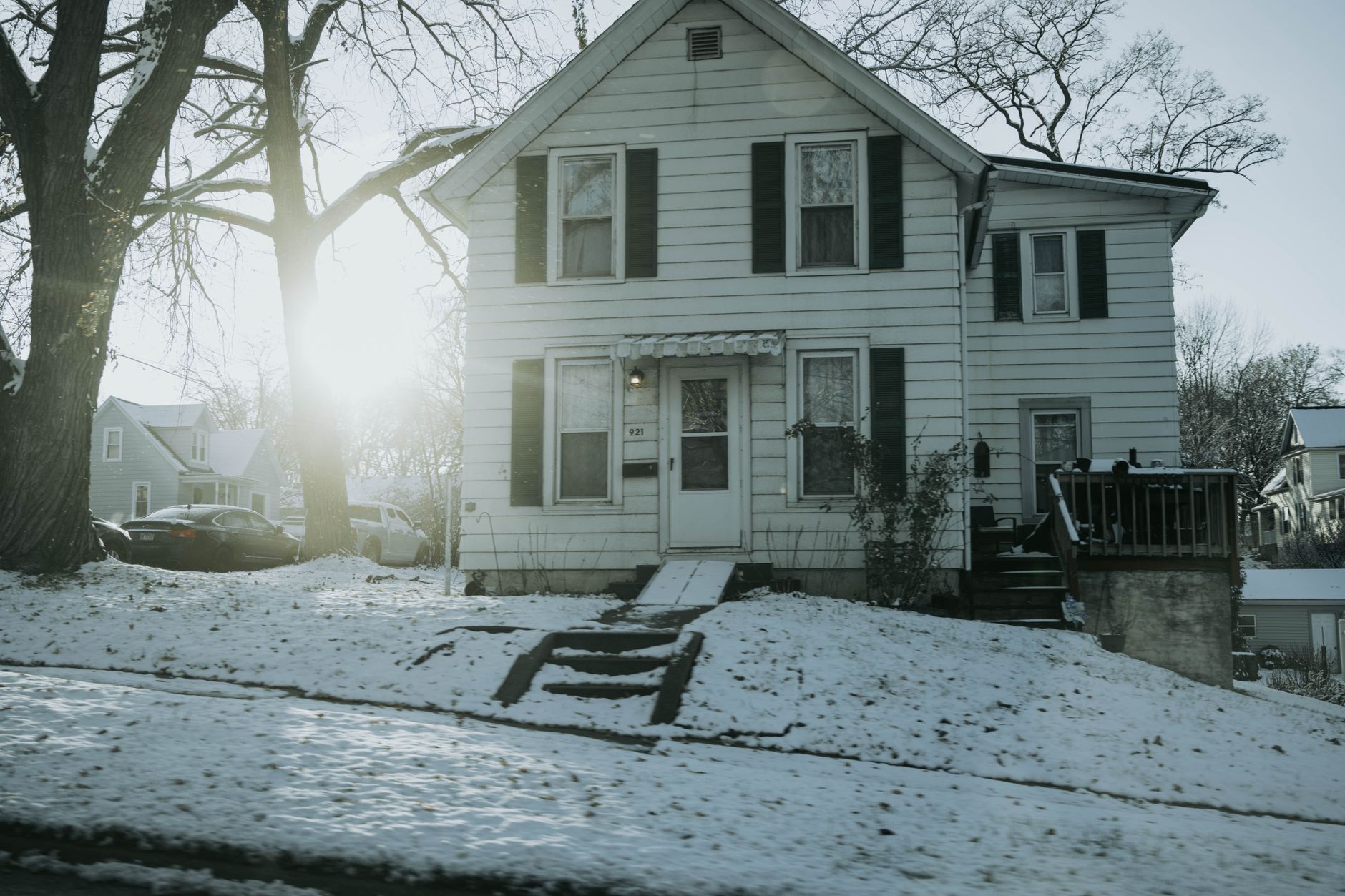 A suburban house in Dixon, IL covered with fresh winter snow and sunlight shining through trees.
